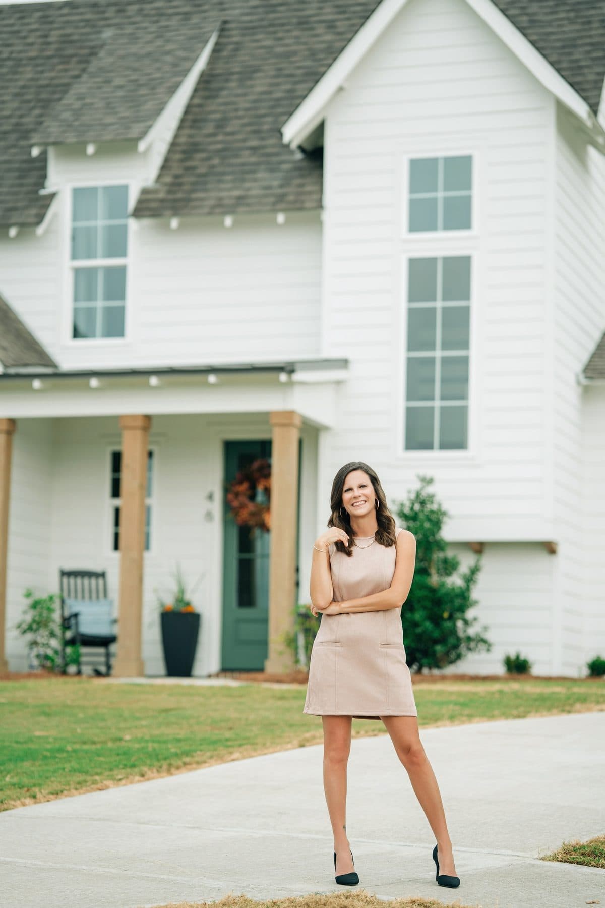 Shana Genenbacher in front of a white farmhouse-style home